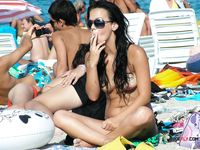 Kouří a topless opaluje mezi plážujícími na klidném břehu