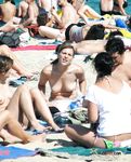Dove la sabbia incontra il mare in una giornata luminosa con una bagnante topless