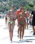 Dove la sabbia incontra il mare in una giornata luminosa con una bagnante topless