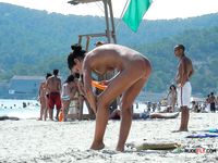 Dazzling blonde with a slim body and small tits walks around the beach topless 2