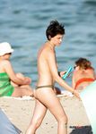 Holding a Wooden Board at a Topless Beach