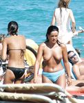 Oranžové spodní díly plavky při topless procházce mělkou vodou