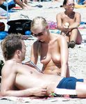 She takes photos with her camera with her perky tits out while another dashing brunette nearby also enjoys her day topless 4