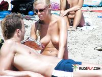 She takes photos with her camera with her perky tits out while another dashing brunette nearby also enjoys her day topless 4