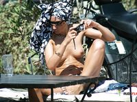 Oben ohne im Strandwasser – Sonnenbrille in der Hand