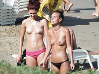 Nude Sunbathing on a Sandy Beach Among Summer Beachgoers