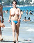 This dashing hottie with seductive curves sits in the sand topless and sunbathes her perfect breasts