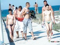 Colorful Umbrellas Dot the Beach Around Her Topless Sunbathing