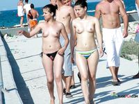 Colorful Umbrellas Dot the Beach Around Her Topless Sunbathing