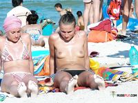 Colorful Umbrellas Dot the Beach Around Her Topless Sunbathing