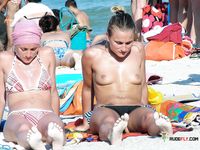 Colorful Umbrellas Dot the Beach Around Her Topless Sunbathing