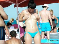 Colorful Umbrellas Dot the Beach Around Her Topless Sunbathing