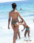 Topless Beachgoers Socialize on a Sunny Day by the Sea