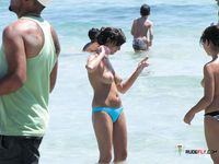 Topless Beachgoers Socialize on a Sunny Day by the Sea