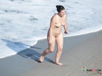 Naturist girl on a naked beach takes off her bra 2