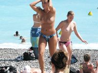 She sits in the sand sunbathing her magnificent, natural breasts and her smooth snatch