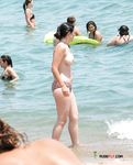 She Fixes Her Black Bikini on a Sunny Umbrella Beach