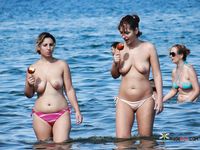 Topless Woman Walks a Busy Beach Under the Summer Sun