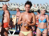 Topless Woman Walks a Busy Beach Under the Summer Sun