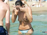 Two Nudists Share a Quiet Moment on a Pebble Beach