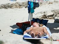 A sensual couple enjoys their day at the beach among a nudist colony while the sun heats their attractive, naked young bodies 2