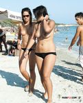 Slim and attractive ladies with bubbly asses and natural tits sit in the sand or walk around sunbathing