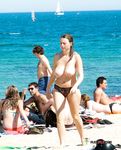 De ene topless, de andere in bikini tijdens een drukke strandwandeling