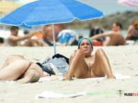 Busty nudist lady at a naked beach is just hanging around with her boobs out 2