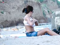 Capturing the graceful silhouette of a lady enjoying the ocean breeze in a topless fashion.