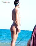 Basking in the intense heat of the shore while enjoying a clothing-optional lifestyle.