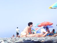 Two Nude Women Stroll a Quiet Pebble Beach