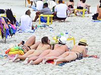 Two Nude Women Stroll a Quiet Pebble Beach