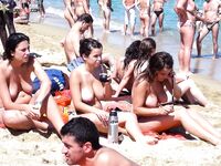 Tomando el sol topless sobre una toalla en una costa animada