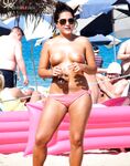 Tomando el sol topless sobre una toalla en una costa animada