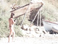 Nude Woman and Towel-Wrapped Man at a Nudist Beach