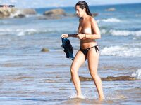 The natural light of the coast accentuating the beauty of a topless model on the beach.