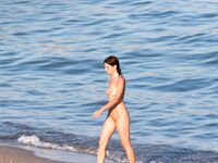Serene Nude Rest on Sandy Shore Framed by Coastal Rocks