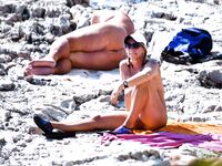 Sunlit Shoreline Nude Beach Pose with Dark Sunglasses