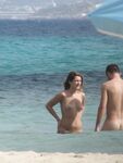 Laughing Topless Beach Sitter in Purple Bikini Bottoms