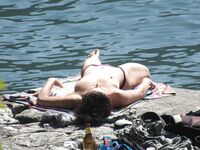 Laughing Topless Beach Sitter in Purple Bikini Bottoms