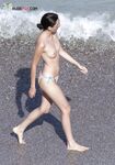 A woman enjoying the view of the waves in a relaxed topless state.