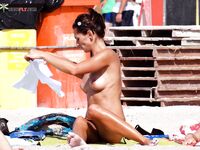 A woman enjoying the view of the waves in a relaxed topless state.