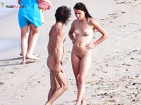Topless op een druk zonnig strand tussen andere strandgangers