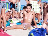 Topless op een druk zonnig strand tussen andere strandgangers