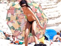 A lady enjoying a tropical-style waterfront in a traditional, topless European manner.