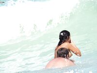 A breathtaking view of the coastline where a lady is seen relaxing in a natural, topless state.