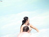 A breathtaking view of the coastline where a lady is seen relaxing in a natural, topless state.