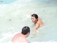 A breathtaking view of the coastline where a lady is seen relaxing in a natural, topless state.