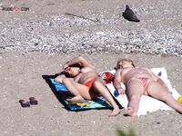 Een topless pose buiten met sieraden tegen een blauwe lucht