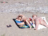 Een topless pose buiten met sieraden tegen een blauwe lucht